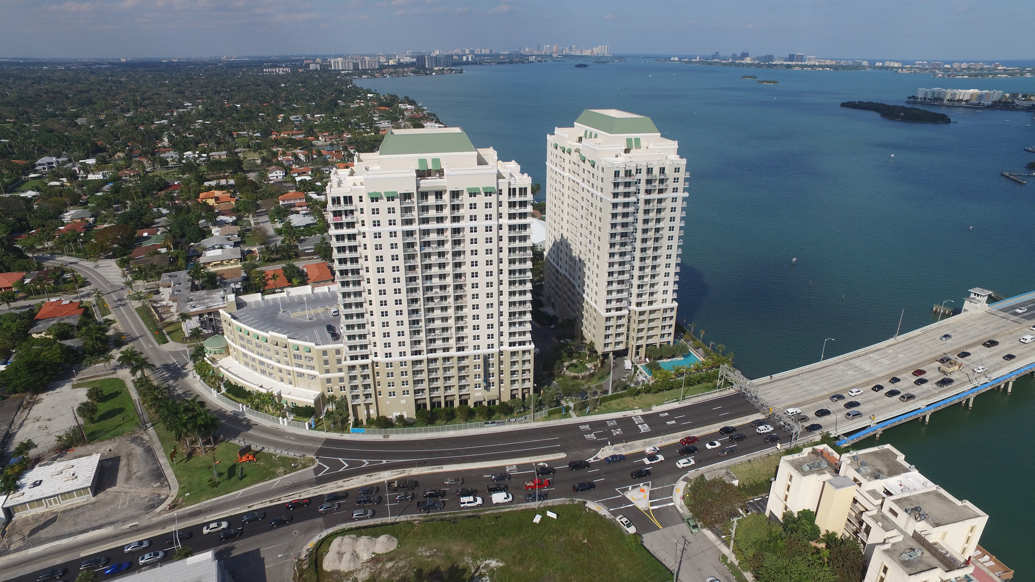 Aerial view of two waterfront high rise apartment buildings and causeway.